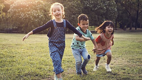 Three children playing outside on the grass.