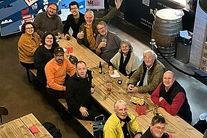 photo taken from above of people sitting at a long table in the brewery