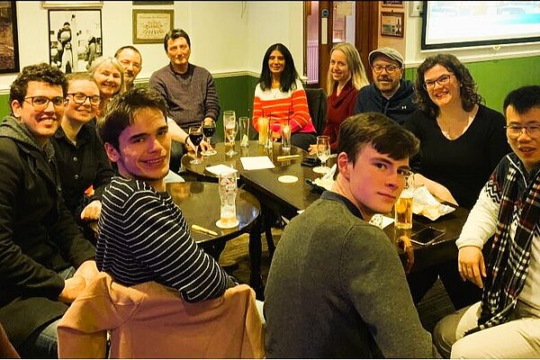 group of people sitting around a pub table 